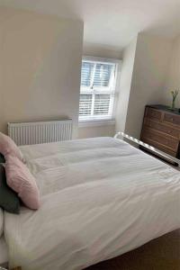 um quarto com uma cama branca, uma cómoda e uma janela em Cosy Cottage, Nr Betws y Coed. em Llanrwst