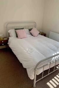 een bed met roze en witte kussens erop bij Cosy Cottage, Nr Betws y Coed. in Llanrwst