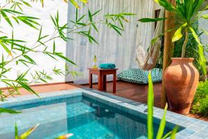 a swimming pool in the middle of a yard with plants at Vila de Charme in São Miguel do Gostoso