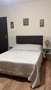 a bedroom with a large bed with white sheets at Hotel Estância in Poços de Caldas