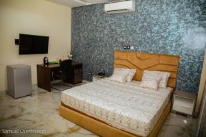 a bedroom with a bed and a desk and a television at Complexe Hôtelier AnD in Ouagadougou