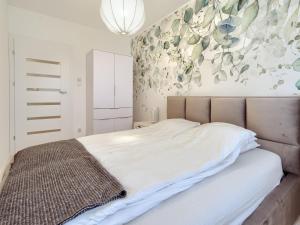 een slaapkamer met een bed met een schilderij aan de muur bij Tricity Retreat Apartments by Rentujemy in Straszyn