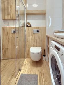 a bathroom with a toilet and a glass shower at Tricity Retreat Apartments with Parking - by Rentujemy in Straszyn