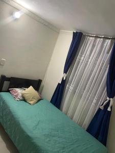 a bedroom with a bed and a window with blue curtains at Linda habitación buena ubicación in Bogotá