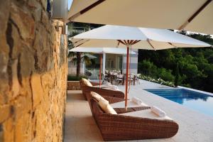 eine Terrasse mit Stühlen und einem Sonnenschirm neben einem Pool in der Unterkunft Zeno Suites in San Zeno di Montagna