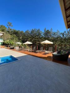 a patio with chairs and umbrellas and a swimming pool at Pousada Mar Mineiro Macacos in Nova Lima