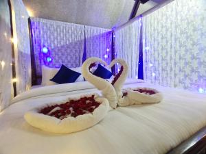 dois cisnes em forma de corações estão sentados numa cama em PV Cottages Serenity Beach em Pondicherry
