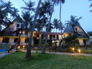 a resort with palm trees in front of it at PV Cottages Serenity Beach in Pondicherry