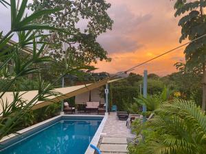 a house with a swimming pool with a sunset in the background at Lovely studio-apartment near the beach in Uvita