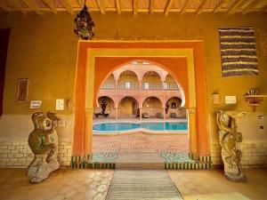 an indoor swimming pool in a building with an archway at Maison Merzouga Guest House in Merzouga