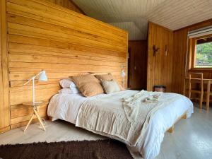 a bedroom with a large bed with a wooden wall at Peuma Lodge Patagonia in Futaleufú