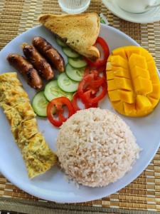 einen Teller mit Reis, Fleisch und Gemüse in der Unterkunft Sarah's Garden BnB & Spa in Clarin