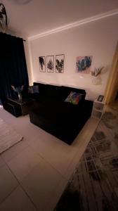 uma sala de estar com um sofá preto e quadros na parede em Relaxing madinaty em Madinaty