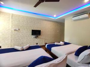 a room with two beds and a tv on the wall at PV Cottages Serenity Beach in Pondicherry