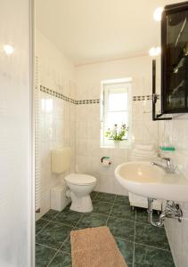 a white bathroom with a toilet and a sink at Ferienwohnung Reimers in Boltenhagen