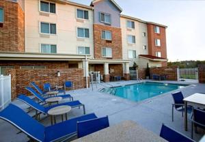 a hotel with a pool and chairs and a building at TownePlace Suites by Marriott Little Rock West in Little Rock