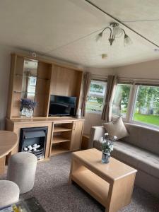 ein Wohnzimmer mit einem Sofa und einem TV in der Unterkunft Holiday home at Parkdean Cherry Tree Holiday Park 627 in Great Yarmouth