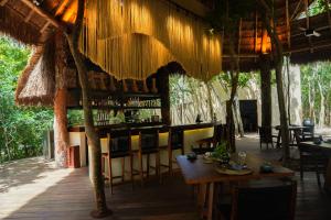 een restaurant met een bar met tafels en stoelen bij Oriundo Luxury Nature Villas in Valladolid