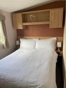 a bedroom with a large white bed with a wooden headboard at Holiday home at Parkdean Cherry Tree Holiday Park 627 in Great Yarmouth