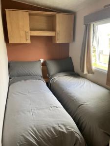 two beds in a small room with a window at Holiday home at Parkdean Cherry Tree Holiday Park 627 in Great Yarmouth +2 photos
