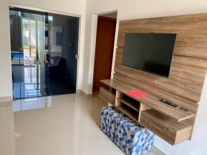 ein Wohnzimmer mit einem TV an einer Holzwand in der Unterkunft Casa com piscina e duas suítes perto do Parque Lagoa Quente in Caldas Novas