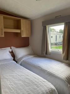 2 Betten in einem kleinen Zimmer mit Fenster in der Unterkunft Holiday home at Parkdean Cherry Tree Holiday Park 627 in Great Yarmouth