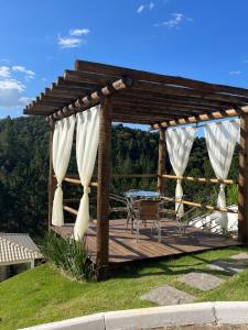 a wooden deck with a table and white curtains at Pousada Mar Mineiro Macacos in Nova Lima