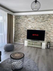 a living room with a television and a brick wall at Airport City Zürich in Opfikon