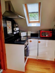 a small kitchen with a red microwave on a counter at Pinecroft Barn - Relax & Unwind! in Storrington