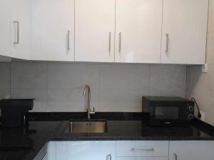 a kitchen with white cabinets and a sink and a microwave at Casinha2 in Amieira