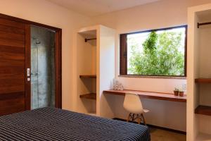 a bedroom with a window and a bed and a chair at Vila de Charme in São Miguel do Gostoso