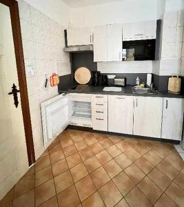a kitchen with white cabinets and a tiled floor at Ferienwohnungen Otto in Sassnitz