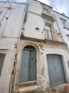 an old building with two doors and a balcony at PalazzOliva - Boho chic Guest house in the historic heart of Martina Franca in Martina Franca