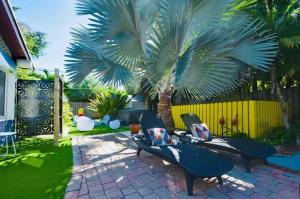 a patio with chairs and a palm tree in a yard at SexyVibe2/private room/out shower/pool/clothin opt in Fort Lauderdale