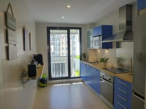 une cuisine avec des placards bleus et une grande fenêtre dans l'établissement Relajate junto al mar en apartamento Cala Alta, à La Cala de Finestra