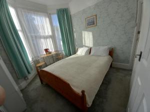 a bedroom with a large bed with green curtains at Mari London Holiday Room in Ilford