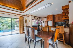 a kitchen and dining room with a wooden table and chairs at Lotus Pool Villa in Rawai Beach
