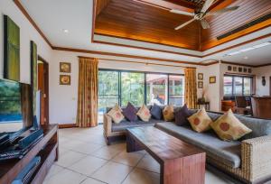 ein Wohnzimmer mit einem Sofa und einem TV in der Unterkunft Lotus Pool Villa in Rawai Beach