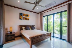 a bedroom with a bed and a large window at Lotus Pool Villa in Rawai Beach