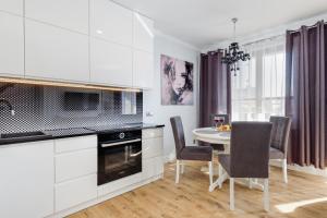 a kitchen with white cabinets and a table and chairs at Wyspa Uznam - Rondo Róży Wiatrów in Świnoujście +35 photos
