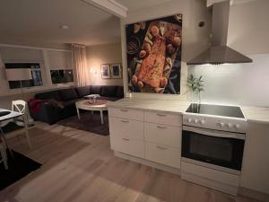 cocina con armarios blancos y sala de estar. en Lena Apartment Tromsø, en Kvaløya