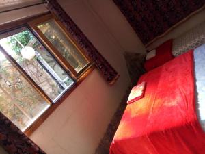 a bedroom with a red bed and a window at Maison d'hotes Ait Bou Izryane in Timoulilt