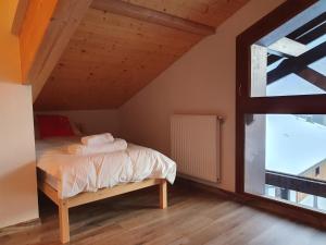 ein Schlafzimmer mit einem Bett und einem großen Fenster in der Unterkunft Le Clos B11 - 3 bedroom apartment 5 minutes walk to the square in Samoëns