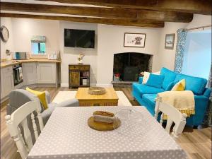 uma sala de estar com uma mesa e um sofá azul em The Cottage at Sychnant Farm em Talgarth