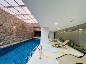 uma piscina com duas cadeiras e uma parede de pedra em Departamento 3 dormitorios 2 baños, 2 TV, Piso Alto, República de El Salvador em Quito