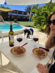 una mujer sentada en una mesa con dos platos de comida y vino en Almendra Residential, en Cabarete