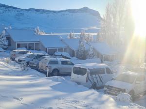 un grupo de autos estacionados en un estacionamiento cubierto de nieve en mountain shadows hotel, en Elliot