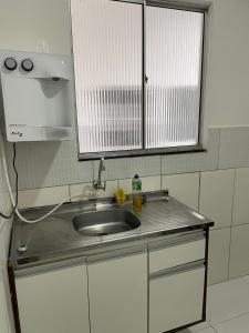 a kitchen counter with a sink and a window at Pousada hostel praia itapua in Salvador