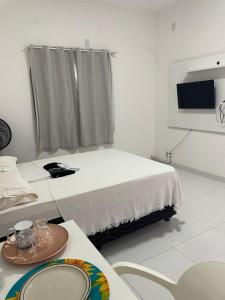 um quarto branco com uma cama e uma televisão em Pousada hostel praia itapua em Salvador