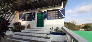uma casa branca com uma porta verde e escadas em Hosteria Farallon Dillon em Ballenita